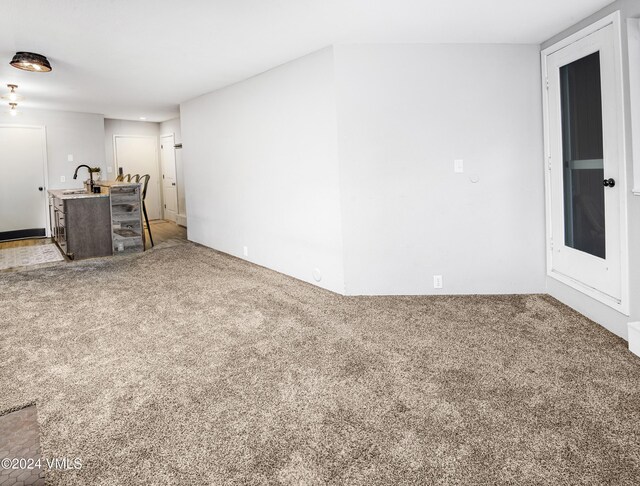 unfurnished living room with sink and carpet flooring