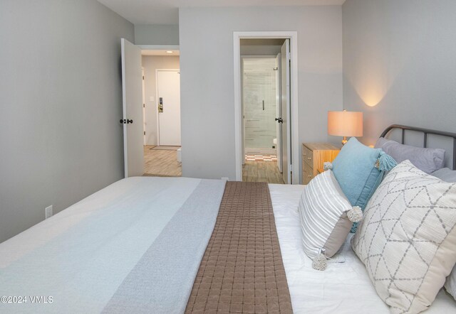 bedroom with ensuite bathroom and light wood-type flooring