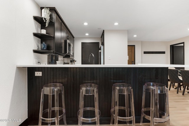 120 Offerson Rd Unit 7320, Beaver Creek, CO 81620 - kitchen with open shelves, light wood-style floors, stainless steel microwave, a kitchen breakfast bar, and a peninsula