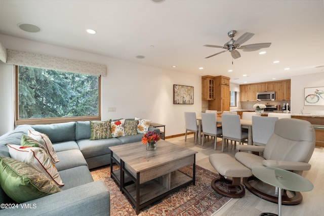 living room featuring sink, light hardwood / wood-style floors, and ceiling fan