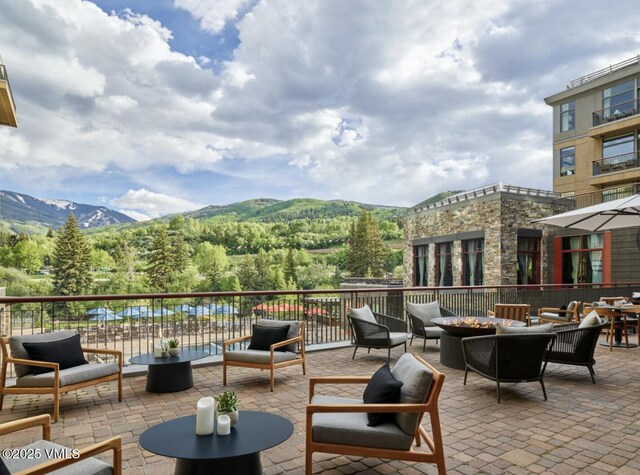 126 Riverfront Ln Unit 345, Avon, CO 81620 - view of patio / terrace with a mountain view, a view of trees, and an outdoor living space with a fire pit