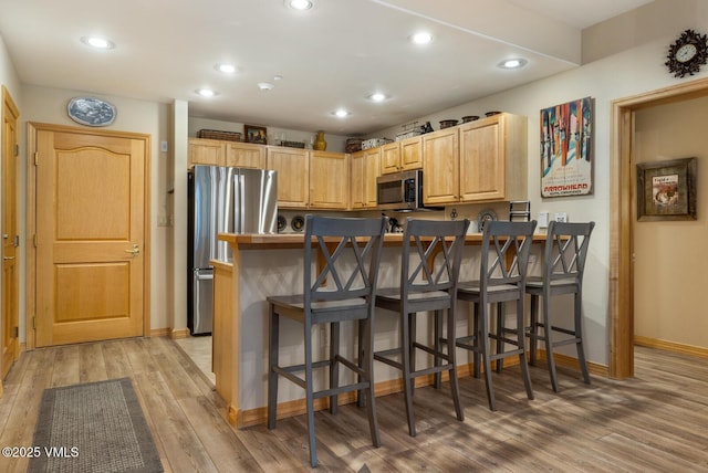 74 Cresta Rd Unit 106, Edwards, CO 81632 - kitchen featuring appliances with stainless steel finishes, light wood-style floors, a breakfast bar area, baseboards, and recessed lighting