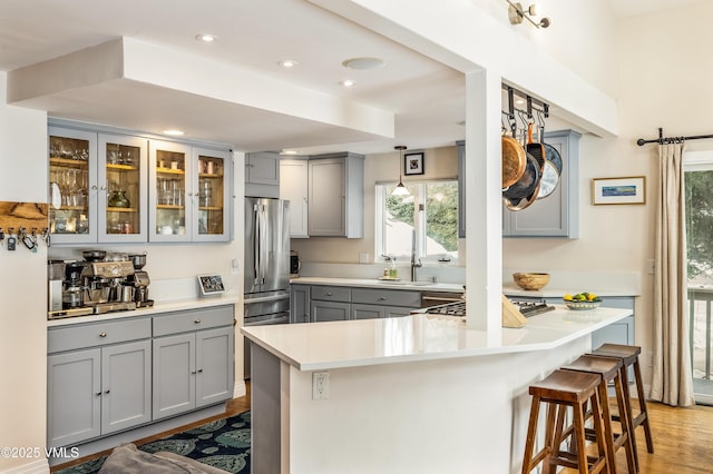 kitchen featuring light countertops, a breakfast bar area, glass insert cabinets, and gray cabinetry