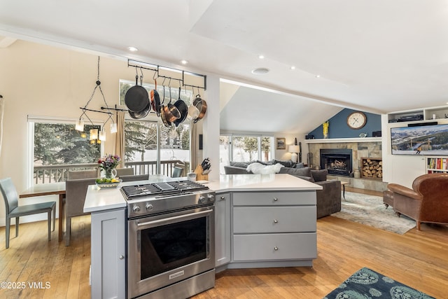 kitchen with light countertops, light wood-style flooring, gray cabinets, and stainless steel gas range