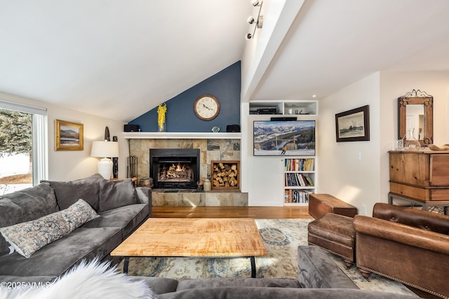 living room featuring vaulted ceiling, a fireplace, and wood finished floors