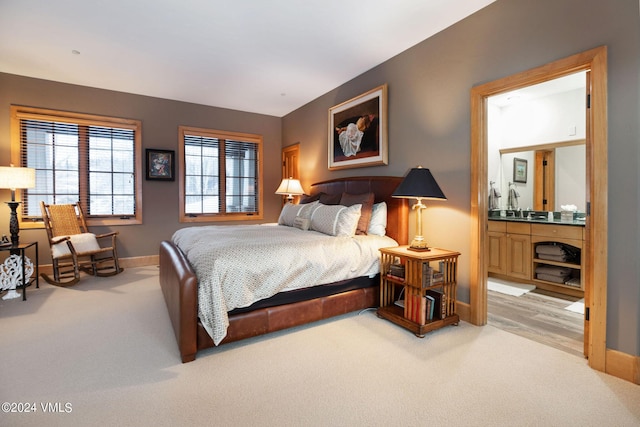 bedroom featuring ensuite bathroom and light carpet