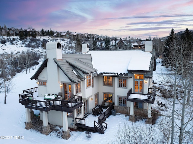 snow covered property with central AC unit, a balcony, and a deck