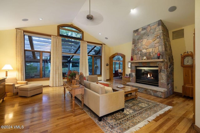 living room with hardwood / wood-style flooring, ceiling fan, a fireplace, and high vaulted ceiling