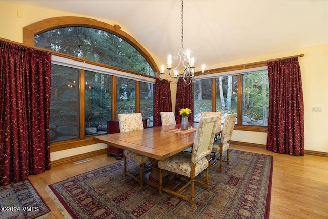 dining room featuring hardwood / wood-style flooring, lofted ceiling, and a notable chandelier