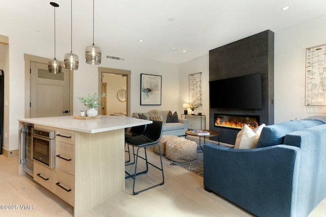 kitchen featuring modern cabinets, light brown cabinets, open floor plan, and a center island