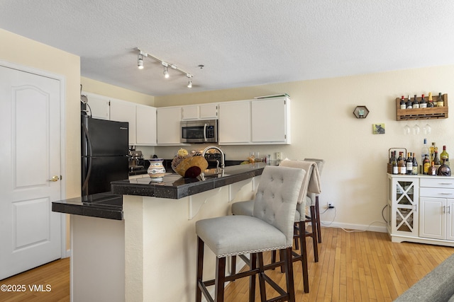 205 Hurd Ln Unit 4311, Avon, CO 81620 - kitchen featuring stainless steel microwave, white cabinetry, a breakfast bar area, and freestanding refrigerator