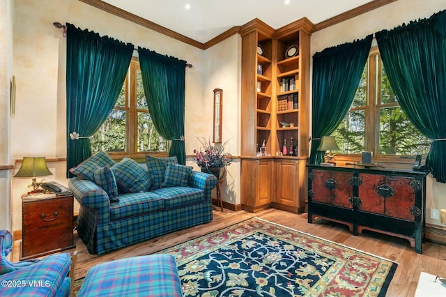 living area with a healthy amount of sunlight, light wood-style flooring, and ornamental molding