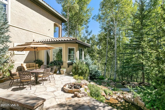 back of property with an outdoor fire pit, a patio area, a tiled roof, and stucco siding