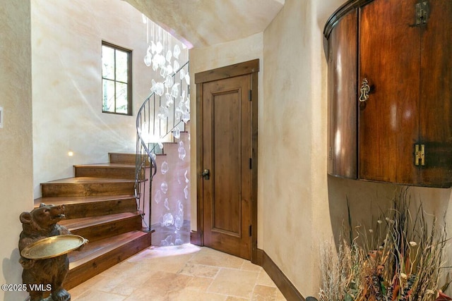 entrance foyer featuring baseboards, stairway, and stone tile floors