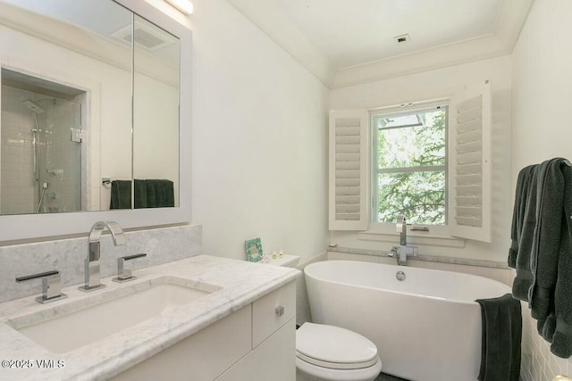 bathroom featuring backsplash, toilet, a stall shower, vanity, and a freestanding tub