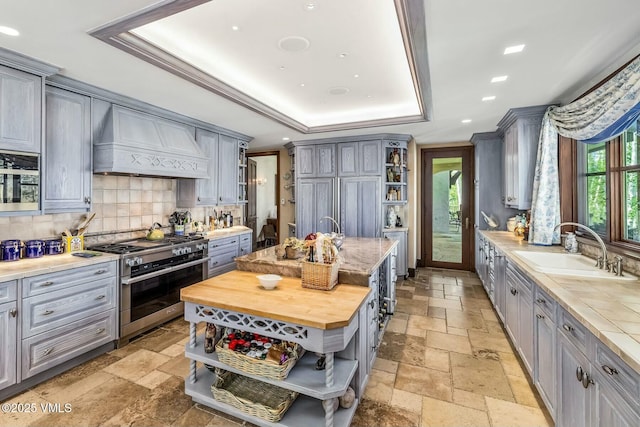 kitchen with custom range hood, open shelves, gray cabinets, and double oven range