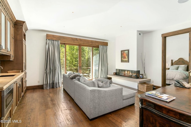 living room featuring a glass covered fireplace, dark wood finished floors, and baseboards