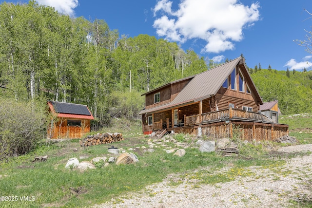 320 Mill, Eagle, CO 81631 - view of front of home featuring a metal roof, log siding, an outbuilding, a forest view, and covered porch