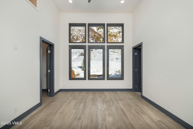 spare room featuring baseboards, a high ceiling, and wood finished floors