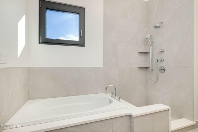 bathroom with a garden tub, a tile shower, and tile walls