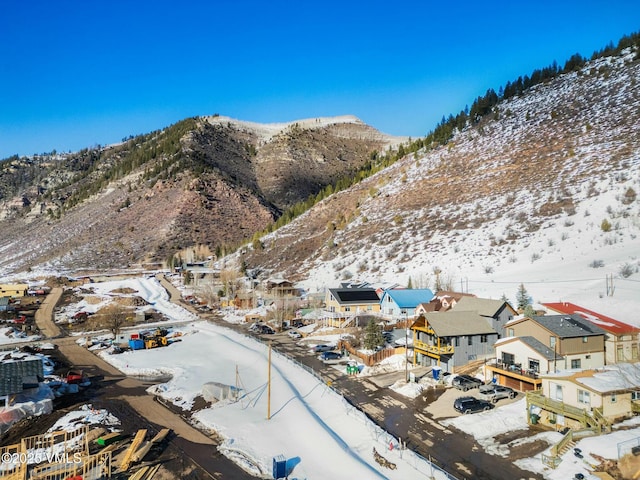 snowy aerial view featuring a residential view and a mountain view