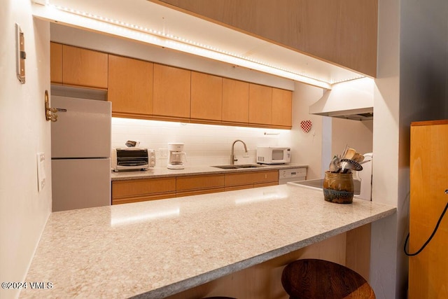kitchen featuring premium range hood, sink, backsplash, kitchen peninsula, and white appliances