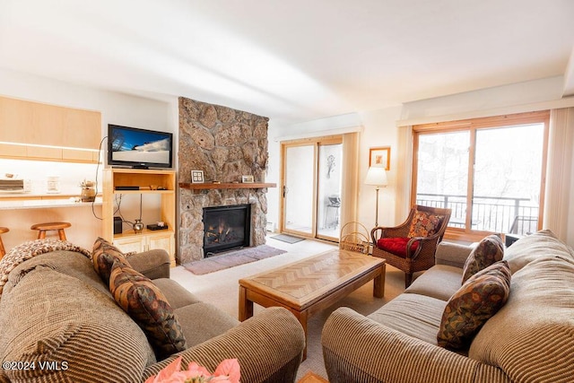 carpeted living room with a stone fireplace