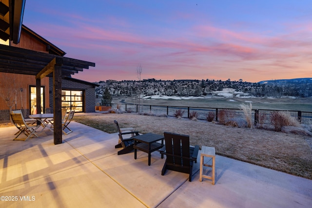 patio terrace at dusk with outdoor dining area, a fenced backyard, and french doors