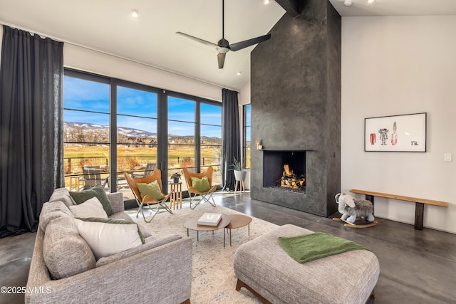 living area featuring concrete floors, recessed lighting, a fireplace, a towering ceiling, and a ceiling fan