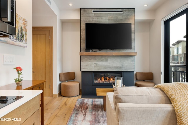 living area with visible vents, recessed lighting, a tile fireplace, and wood finished floors