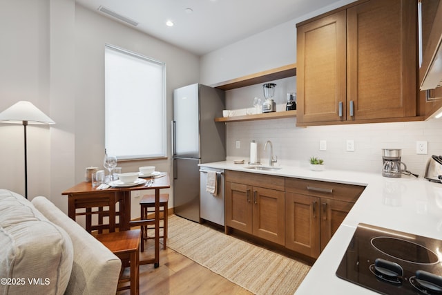 kitchen featuring visible vents, appliances with stainless steel finishes, light countertops, open shelves, and a sink