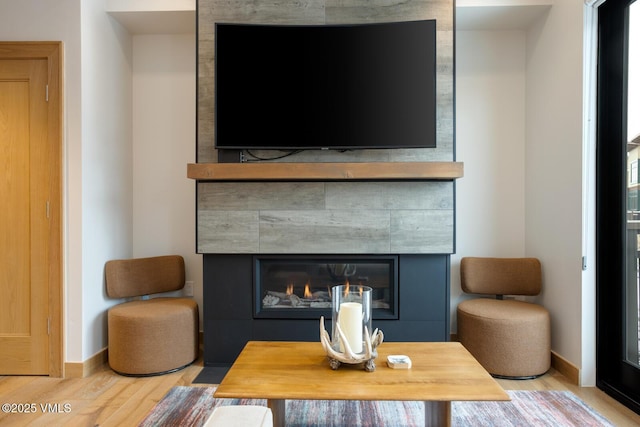 interior space with a fireplace, baseboards, and wood finished floors