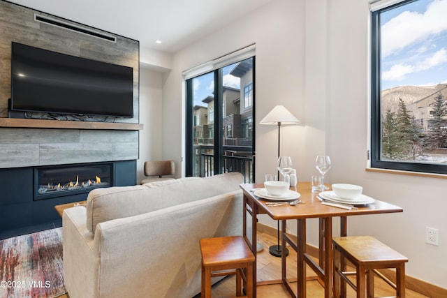 living room with baseboards, wood finished floors, a fireplace, a mountain view, and recessed lighting