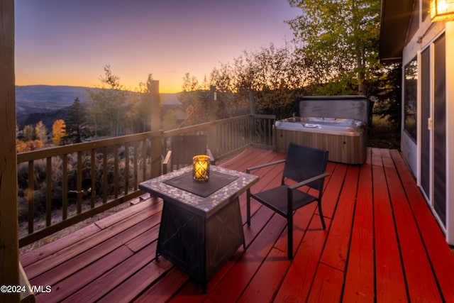 deck at dusk with a mountain view and a hot tub