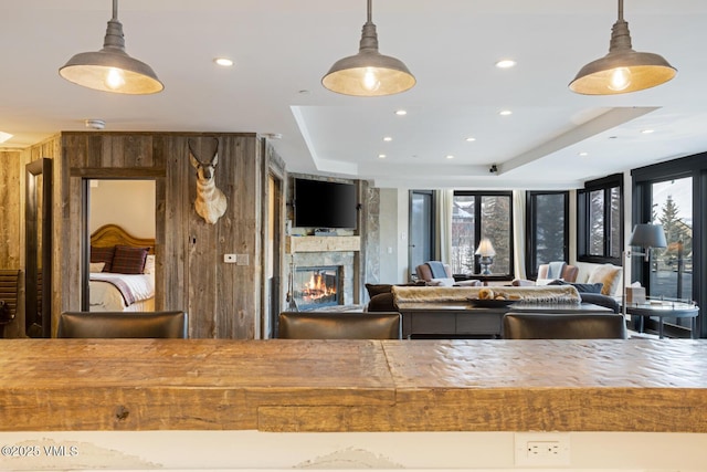 kitchen featuring a large fireplace, pendant lighting, a raised ceiling, and recessed lighting