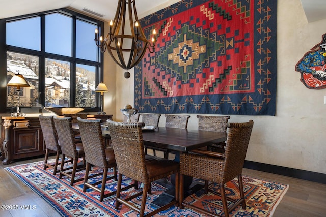 dining room with visible vents, baseboards, hardwood / wood-style flooring, an inviting chandelier, and high vaulted ceiling