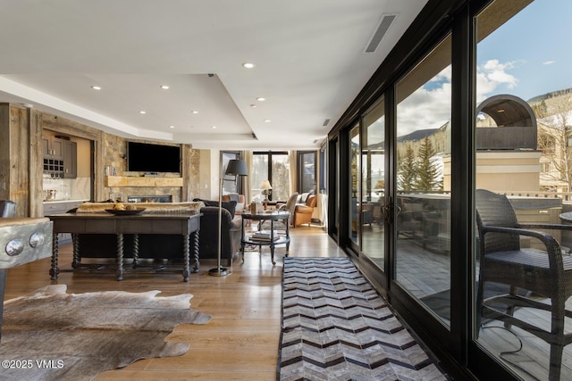 living room featuring light wood finished floors, visible vents, a tray ceiling, a mountain view, and recessed lighting