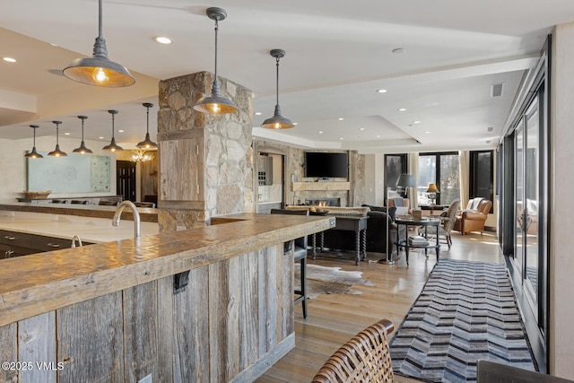 kitchen with a warm lit fireplace, open floor plan, wood finished floors, and recessed lighting