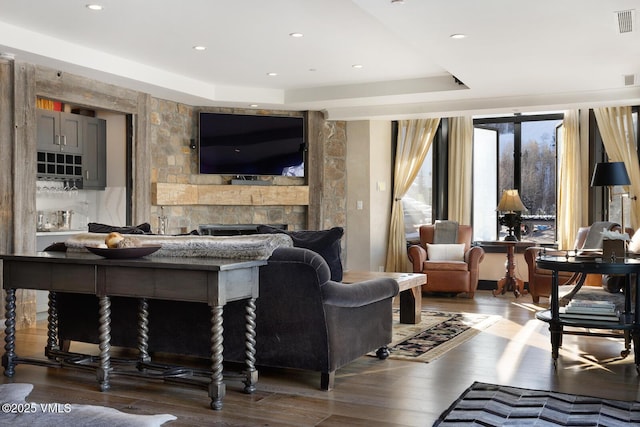 living room featuring a fireplace, a tray ceiling, wood finished floors, and recessed lighting