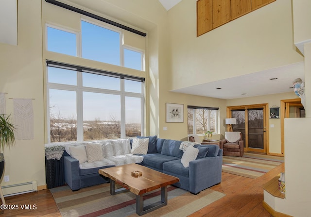living room featuring baseboards, a towering ceiling, wood finished floors, and a baseboard radiator