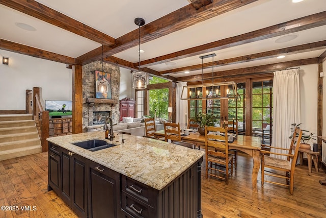922 June Creek Rd, Edwards, CO 81632 - kitchen with a sink, light wood-style flooring, a fireplace, beamed ceiling, and light stone countertops