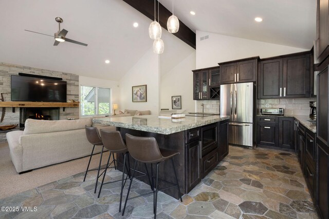 4515 Bighorn Rd, Vail, CO 81657 - kitchen with freestanding refrigerator, open floor plan, stone floors, light stone counters, and a kitchen bar
