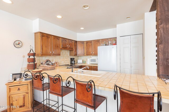 kitchen with white appliances, kitchen peninsula, sink, and a breakfast bar area