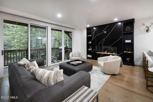 living area featuring a premium fireplace, recessed lighting, baseboards, and wood finished floors