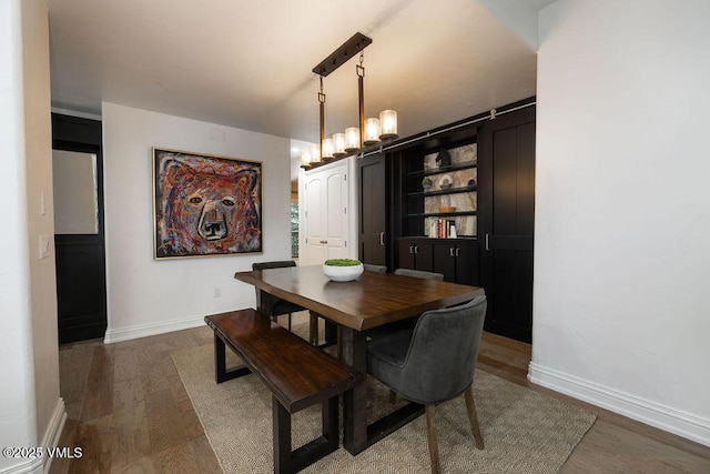 dining room featuring a notable chandelier, baseboards, and wood finished floors