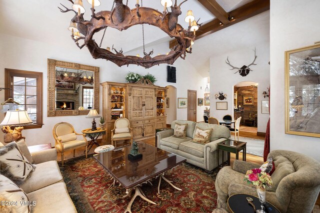 living room featuring wood-type flooring, a towering ceiling, and beam ceiling