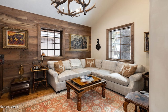 living room featuring plenty of natural light, lofted ceiling, light hardwood / wood-style floors, and wood walls