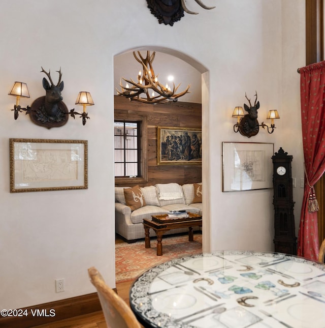 dining room featuring wooden walls, a chandelier, and hardwood / wood-style floors