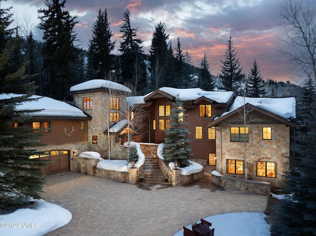 snow covered rear of property featuring a garage