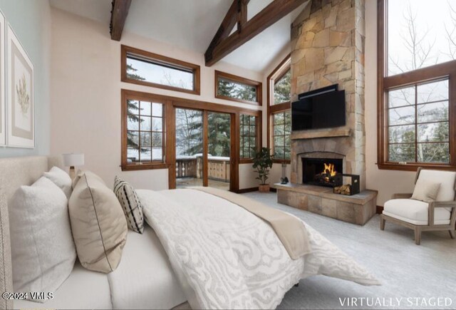 carpeted bedroom with beamed ceiling, a stone fireplace, and high vaulted ceiling